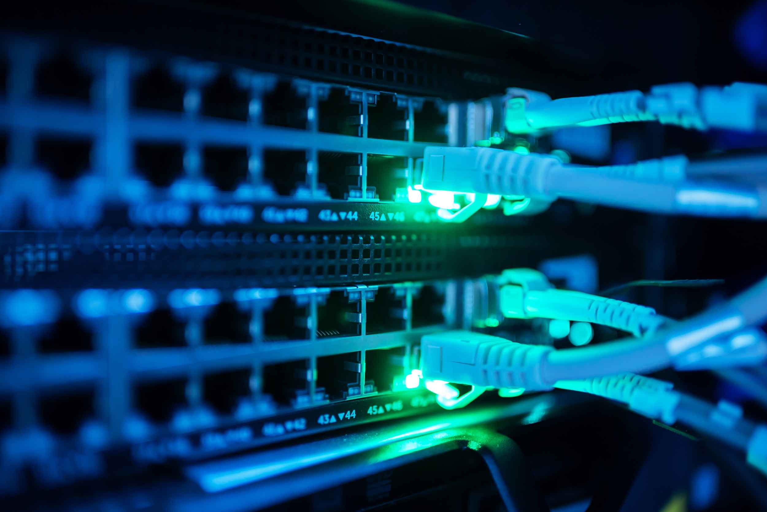 Netzwerkkabel mit leuchtenden Status-LEDs in einem Serverrack